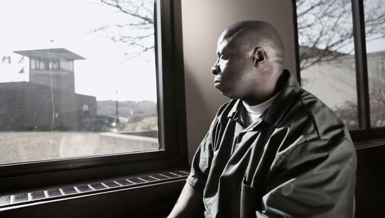 David McCallum III looking out of a prison window towards a guard tower